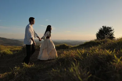 Joyce e Paulo Vinícius de mãos dadas caminhando na colina ao entardecer